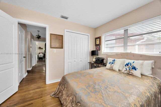 bedroom featuring a closet, wood finished floors, visible vents, and baseboards