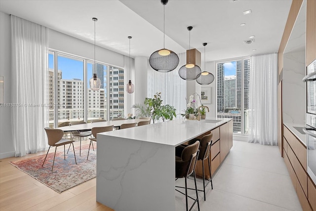 kitchen featuring hanging light fixtures, a large island, modern cabinets, and a city view