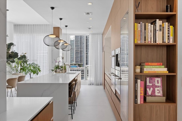 kitchen with a sink, visible vents, light countertops, hanging light fixtures, and modern cabinets