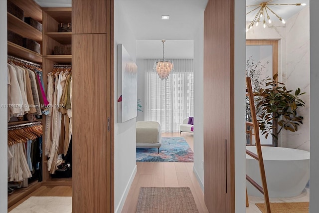 spacious closet featuring a chandelier and light wood-type flooring