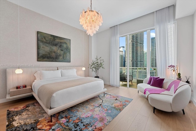 bedroom with access to exterior, a notable chandelier, baseboards, and wood finished floors