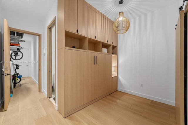 mudroom with light wood finished floors, a barn door, and baseboards