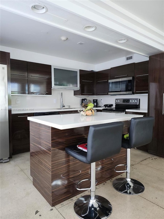 kitchen with modern cabinets, appliances with stainless steel finishes, a kitchen breakfast bar, and light countertops