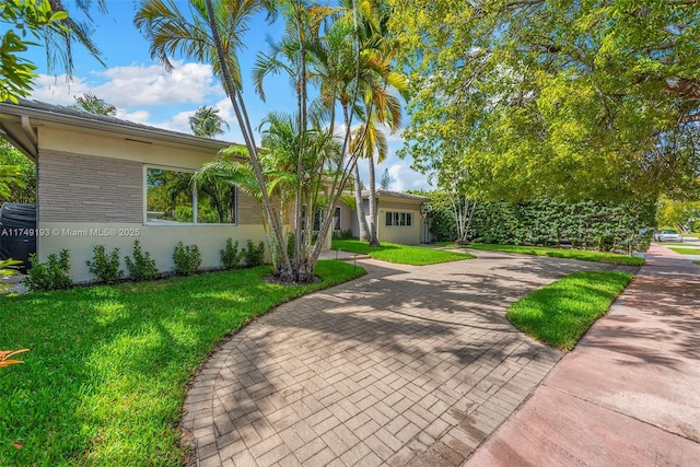 single story home with a front yard, stucco siding, and decorative driveway