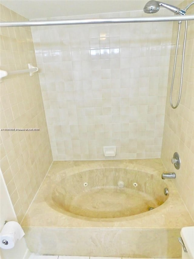 bathroom with a combined bath / shower with jetted tub and toilet