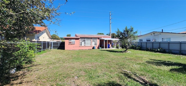 rear view of house featuring a lawn, an outdoor structure, and a fenced backyard