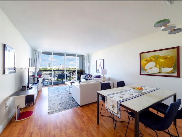 dining room with a wall of windows, wood finished floors, and baseboards