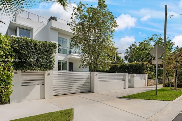 exterior space with a balcony, a fenced front yard, a gate, and stucco siding