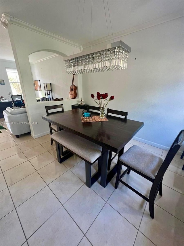 dining space with ornamental molding, arched walkways, baseboards, and light tile patterned floors