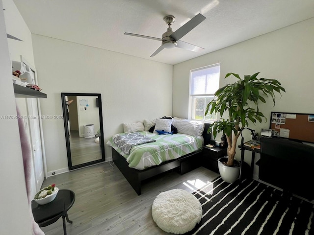 bedroom featuring ceiling fan, baseboards, and wood finished floors