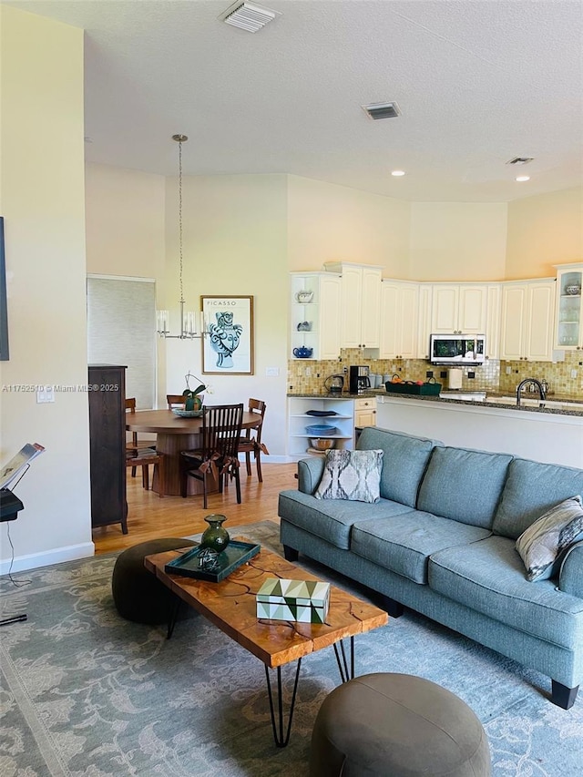 living room with baseboards, recessed lighting, visible vents, and a notable chandelier