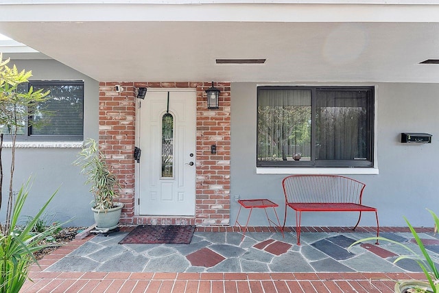 entrance to property featuring brick siding and stucco siding