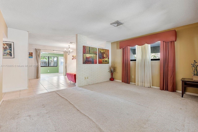 carpeted empty room with a textured ceiling, tile patterned flooring, visible vents, and an inviting chandelier