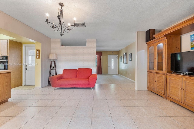 living room with a textured ceiling, light tile patterned flooring, visible vents, and a notable chandelier