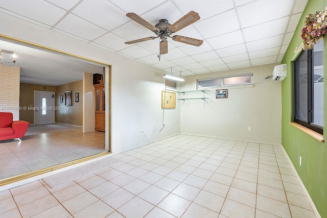 basement with a paneled ceiling, tile patterned flooring, a ceiling fan, and a wall mounted air conditioner