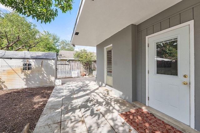 view of exterior entry featuring stucco siding, fence, and a patio