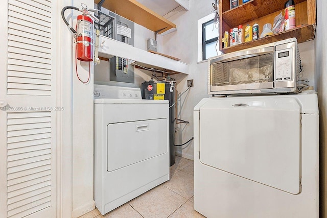 clothes washing area featuring water heater, laundry area, washer and clothes dryer, and light tile patterned flooring