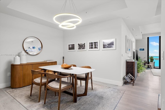 dining room featuring light wood-style floors, baseboards, and a notable chandelier