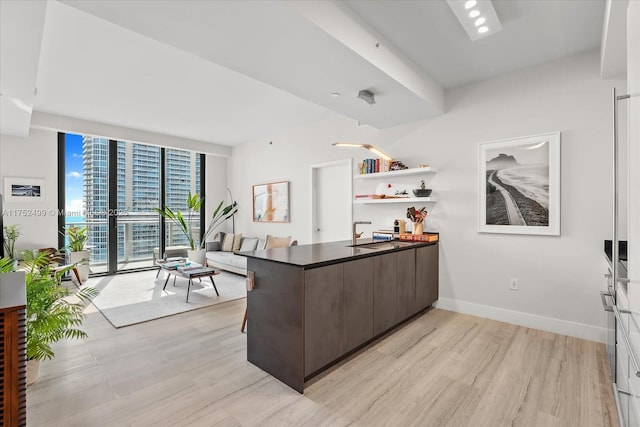 kitchen featuring a peninsula, baseboards, light wood-style floors, dark countertops, and modern cabinets