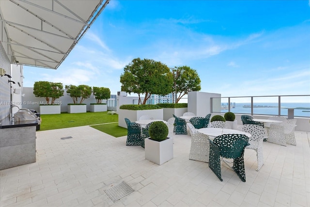 view of patio with exterior kitchen, outdoor dining space, and a water view