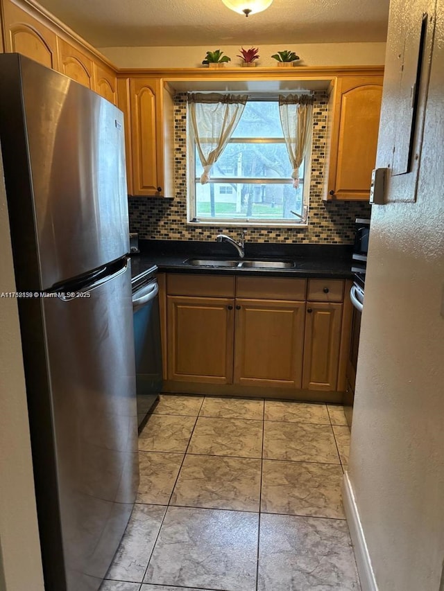 kitchen with dark countertops, decorative backsplash, dishwasher, and freestanding refrigerator