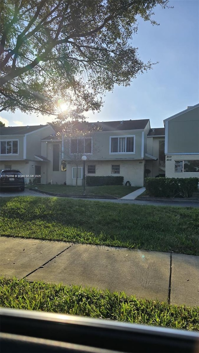 townhome / multi-family property with a front lawn and stucco siding