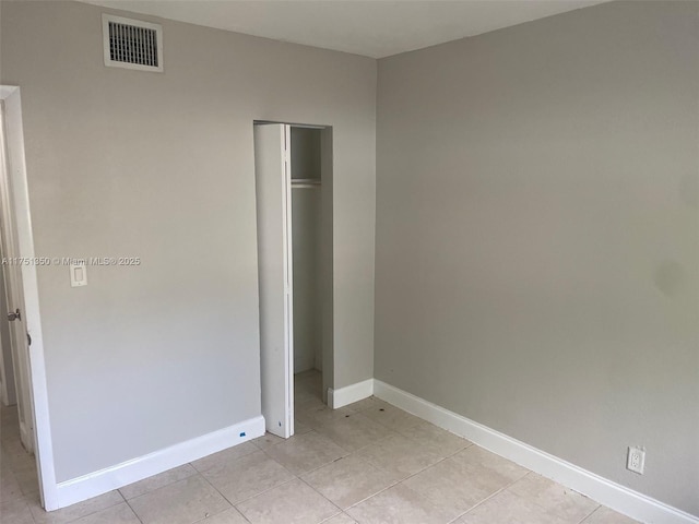 unfurnished bedroom featuring baseboards, visible vents, a closet, and light tile patterned flooring