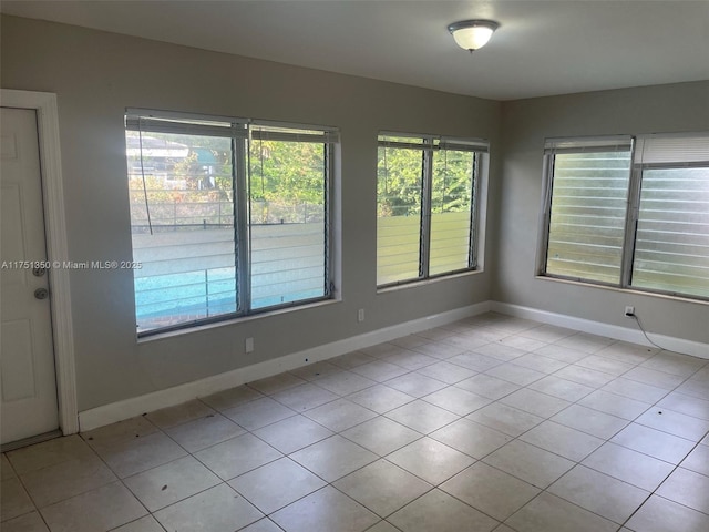 empty room with light tile patterned flooring and baseboards