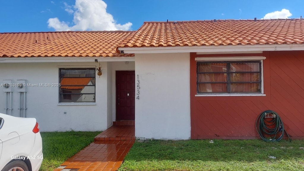 view of front facade featuring a tiled roof and stucco siding