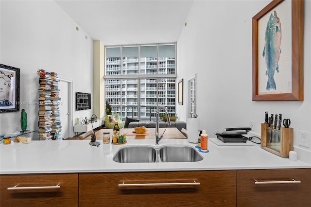 kitchen with light countertops, brown cabinetry, modern cabinets, and a sink