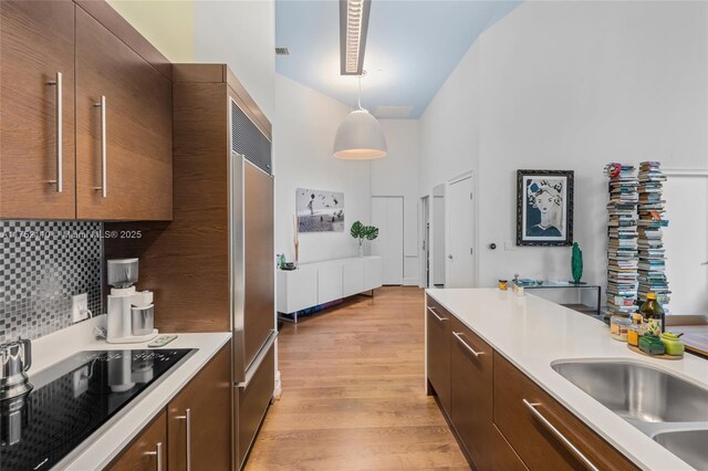 475 Brickell Ave Unit 2809, Miami, FL 33131 - kitchen featuring black electric stovetop, a towering ceiling, light wood-style floors, light countertops, and pendant lighting