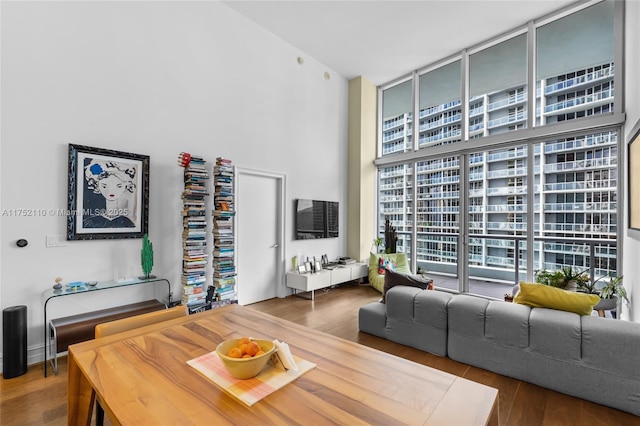 living area with a high ceiling, a wall of windows, and wood finished floors