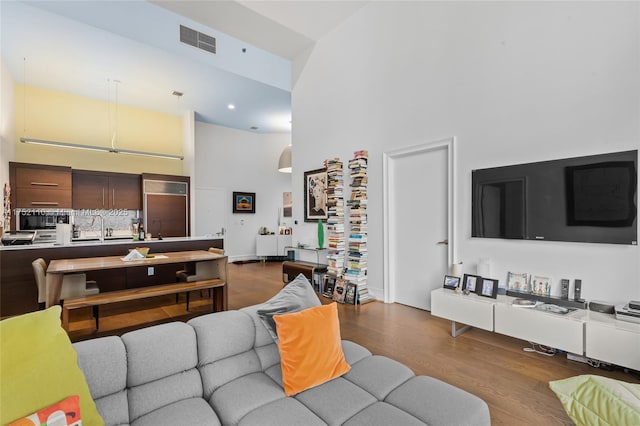 living room featuring visible vents, a towering ceiling, and wood finished floors