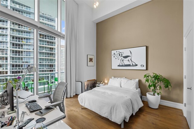 475 Brickell Ave Unit 2809, Miami, FL 33131 - bedroom with multiple windows, wood finished floors, and a high ceiling