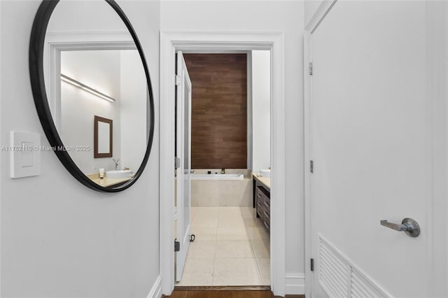 bathroom with a relaxing tiled tub, tile patterned flooring, and vanity