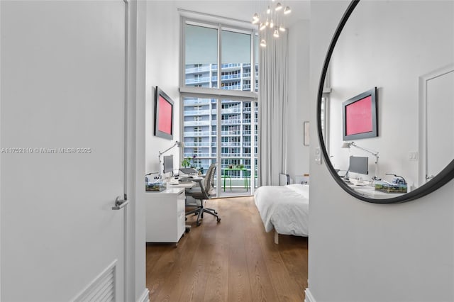 bedroom with a chandelier, floor to ceiling windows, and wood finished floors