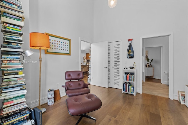 living area with baseboards, a high ceiling, and wood finished floors