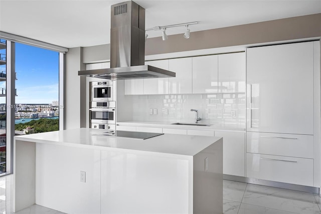 kitchen with modern cabinets, marble finish floor, island exhaust hood, black electric stovetop, and a sink