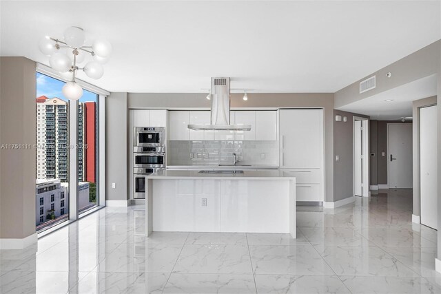 300 Sunny Isles Blvd Unit 4-1208, Sunny Isles Beach, FL 33160 - kitchen featuring modern cabinets, island exhaust hood, white cabinetry, decorative backsplash, and healthy amount of natural light