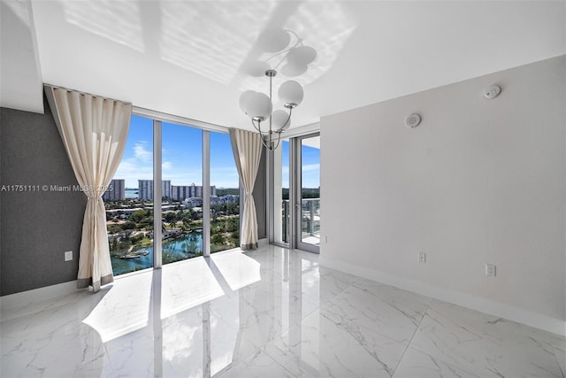 unfurnished room featuring a notable chandelier, a city view, baseboards, marble finish floor, and a wall of windows