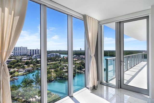 doorway to outside with a wall of windows, marble finish floor, and a water view