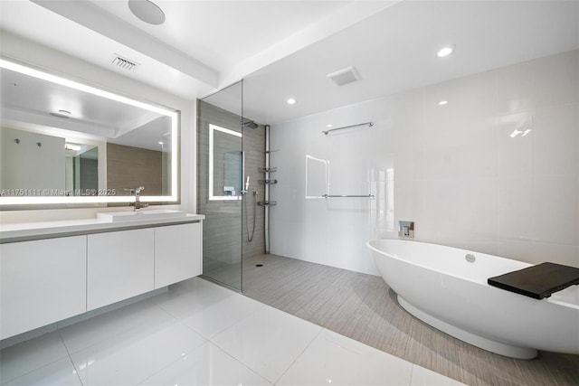 full bathroom featuring a soaking tub, visible vents, walk in shower, and vanity