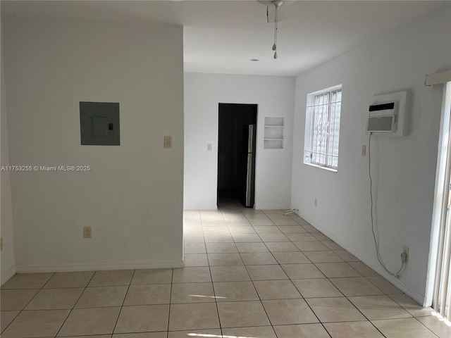 unfurnished room featuring light tile patterned floors, electric panel, baseboards, and a wall mounted air conditioner