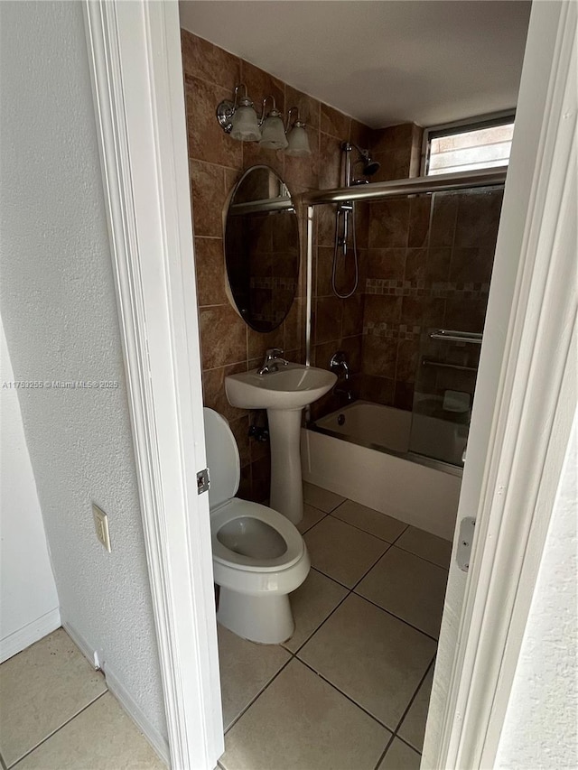 bathroom featuring tile walls, toilet, tile patterned floors, shower / bathtub combination, and a sink