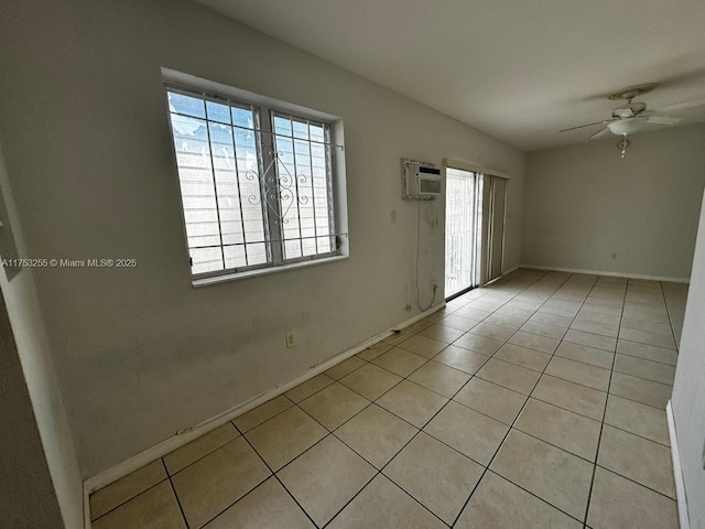 unfurnished room with an AC wall unit, ceiling fan, baseboards, and light tile patterned floors