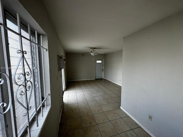 interior space with baseboards, a ceiling fan, and dark tile patterned flooring