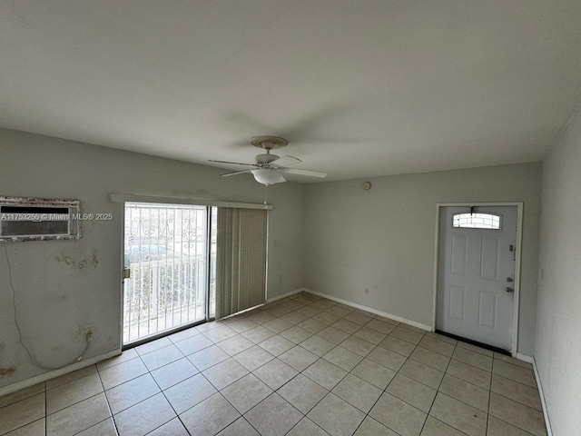 spare room featuring a ceiling fan, a wall mounted air conditioner, baseboards, and light tile patterned floors