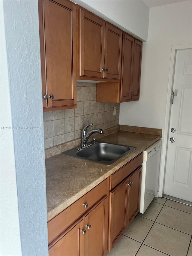 kitchen featuring light tile patterned floors, a sink, decorative backsplash, dishwasher, and brown cabinetry