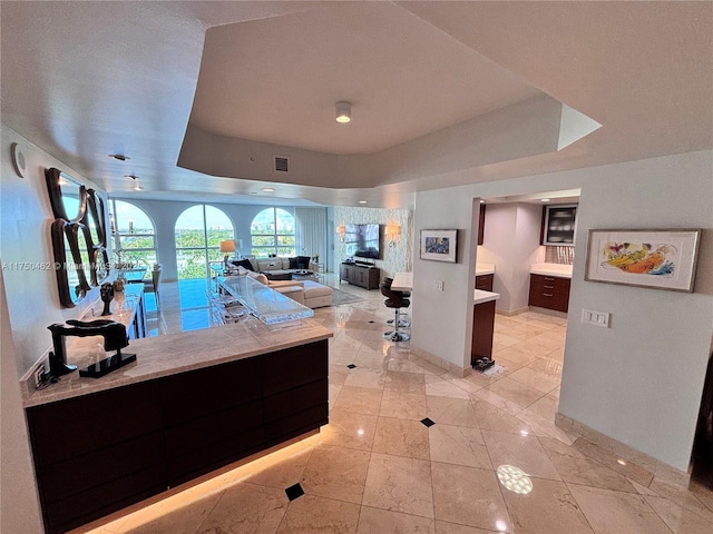 interior space with baseboards, a raised ceiling, and open floor plan