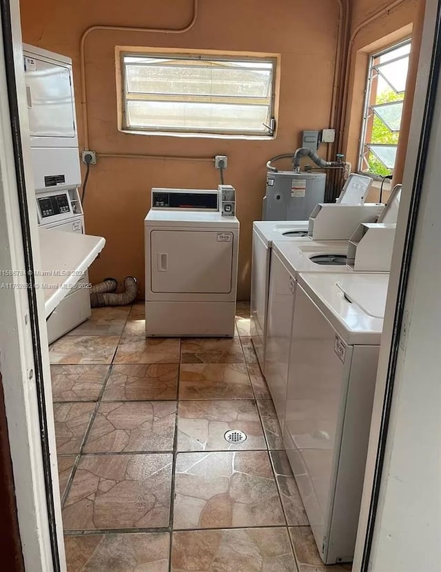 shared laundry area with stone finish floor, gas water heater, and washing machine and clothes dryer